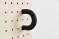 Black size M coloured ring on a birch pegboard