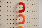 Red and orange coloured rings on a birch perforated panel