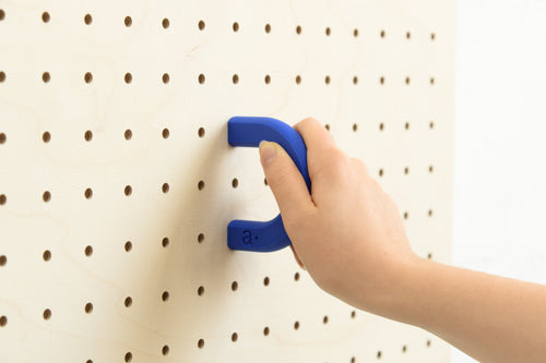 Hand fitting a blue size M coloured ring onto a birch pegboard