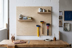 Workshop pegboard above a workbench with hammers hanging from coloured rings
