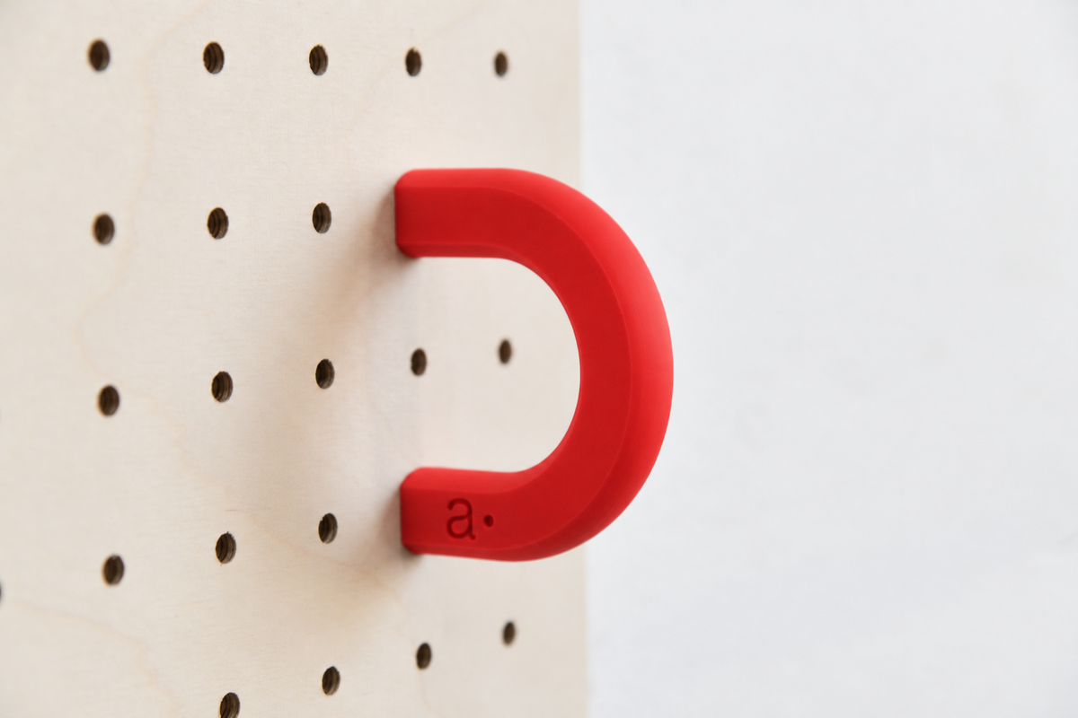 Anneau coloré rouge taille M sur un pegboard en bouleau