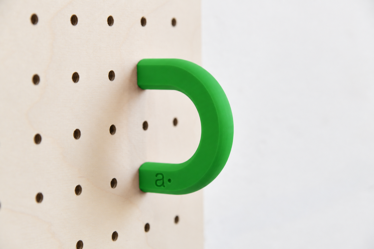 Anneau coloré vert taille M sur un pegboard en bouleau