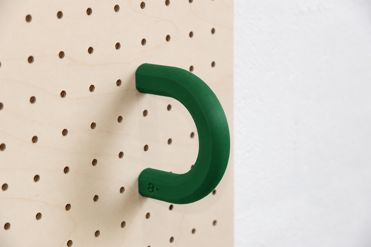 Anneau coloré vert foncé taille L sur un pegboard en bouleau
