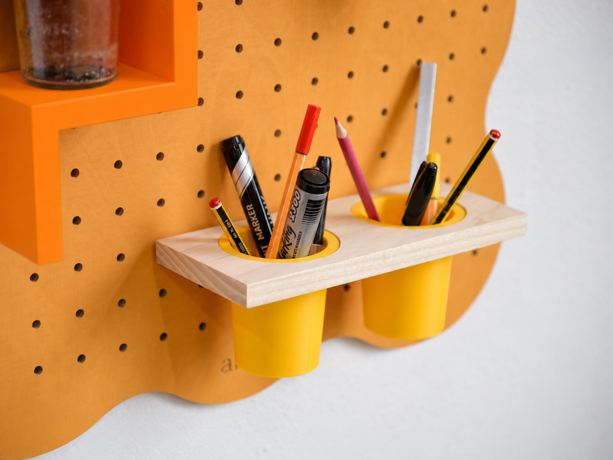 Pot à crayons suspendu double sur pegboard Curves orange pastel, rempli de crayons et feutres