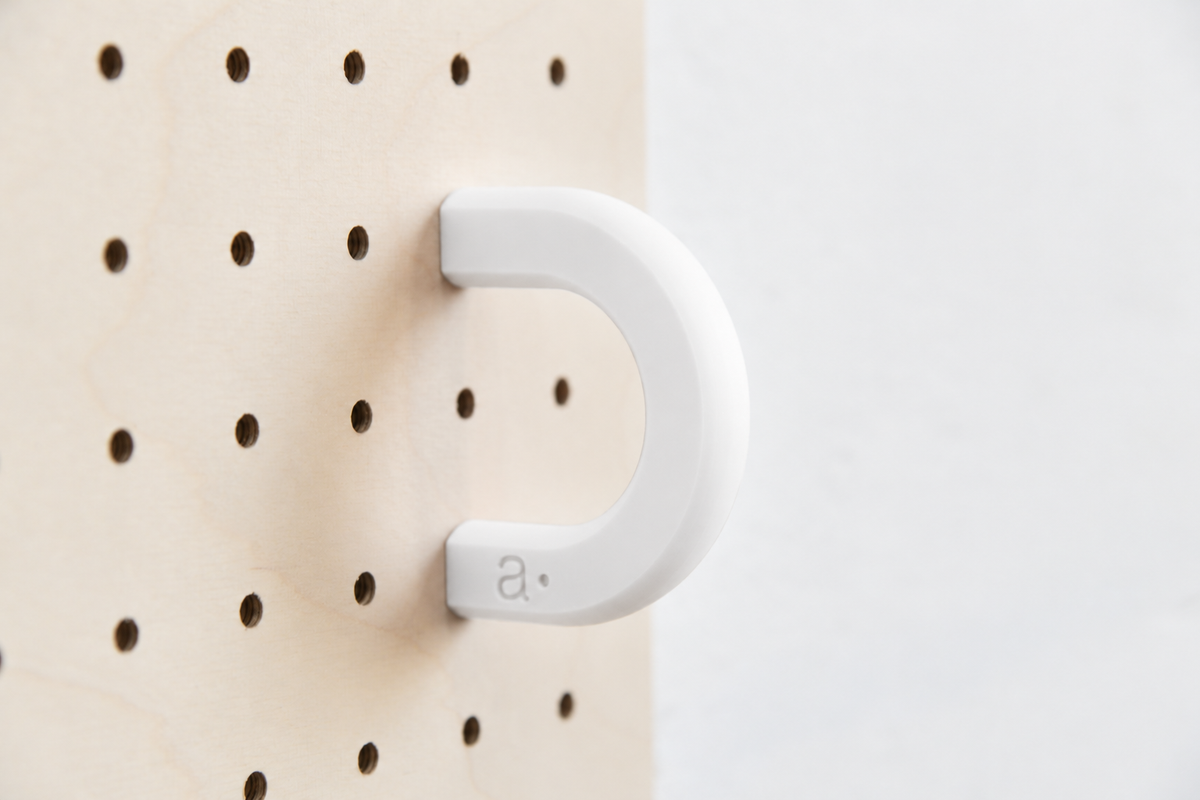 Anilla de color blanco talla M en un pegboard de abedul
