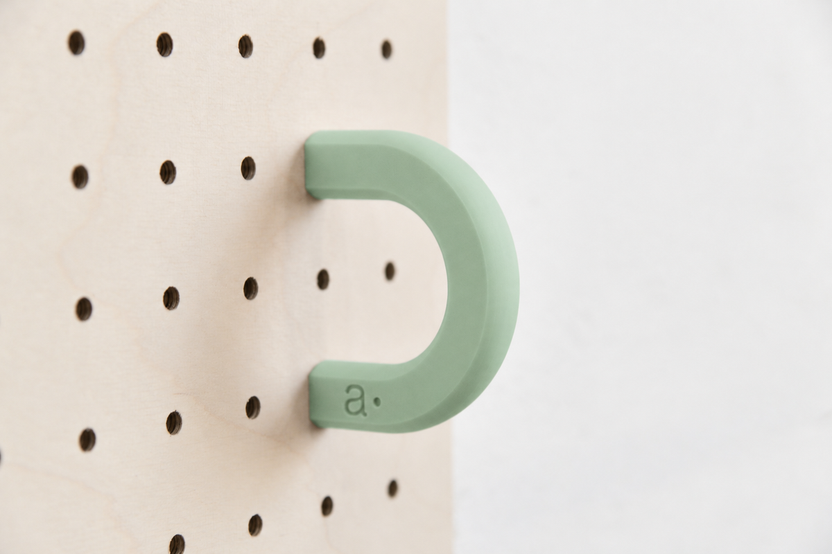 Anilla de color verde salvia talla M en un pegboard de abedul