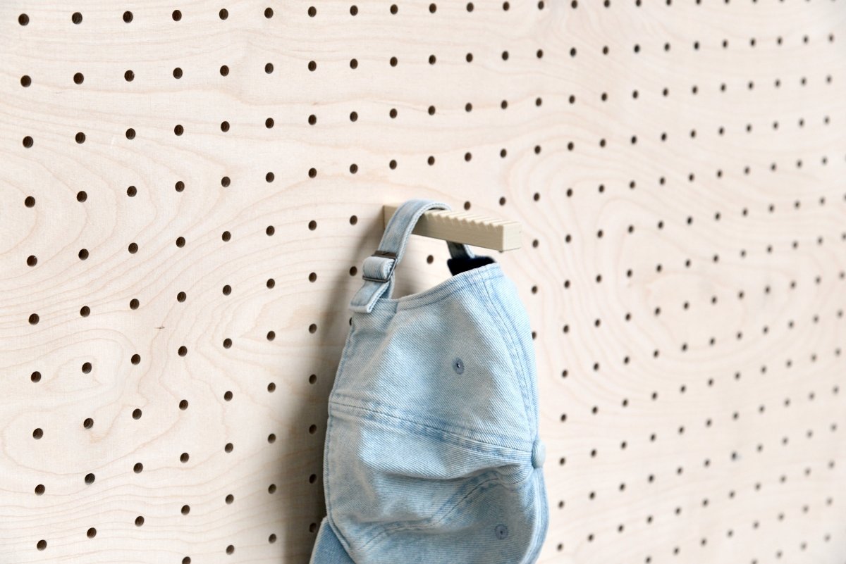Jeanscap am Riemen am Aire Cap-Halter für Pegboard aufgehängt
